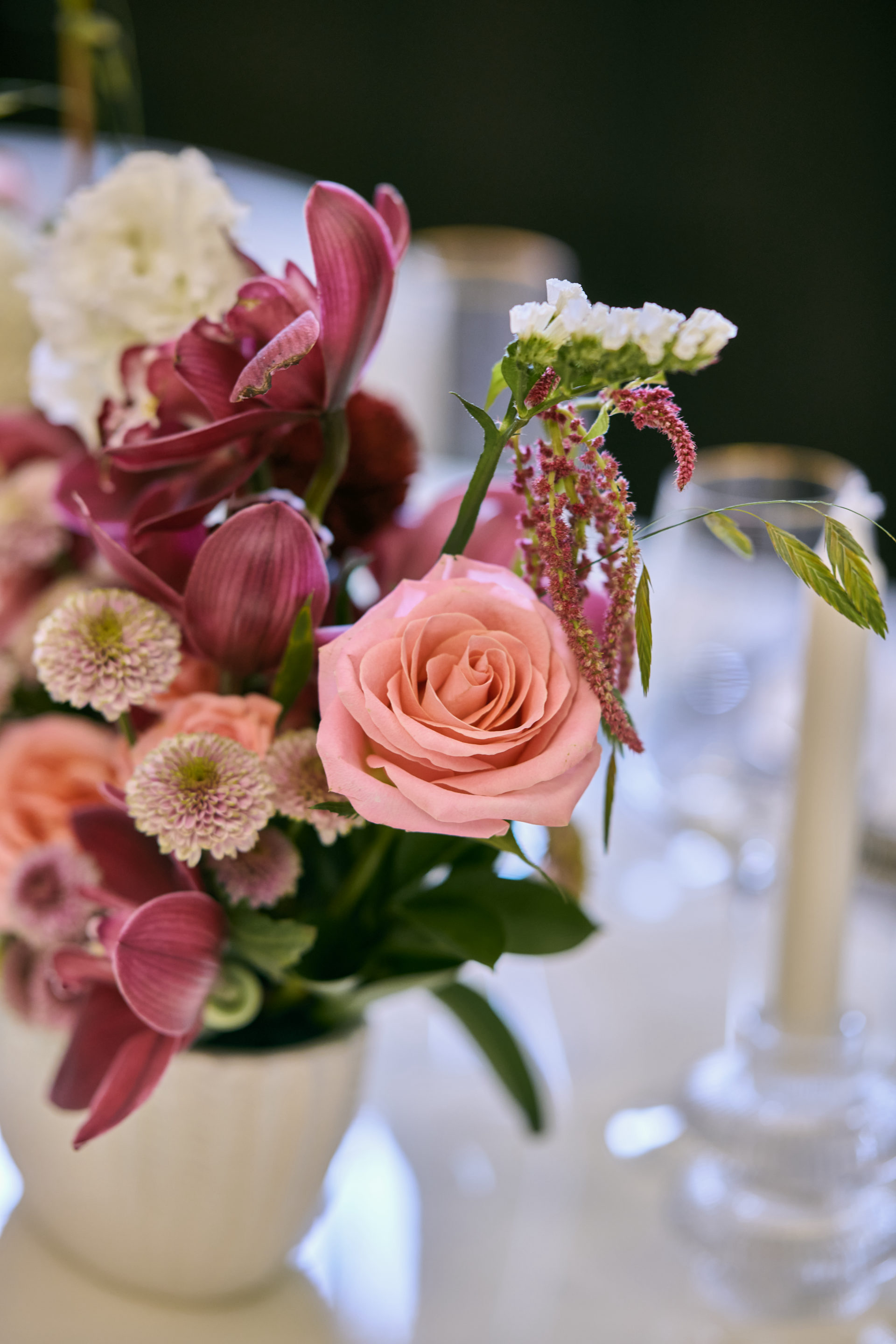 Deep red, pink and white wedding table centerpiece with taper candles at a Dubai reception, by Flower Corner — photo 8