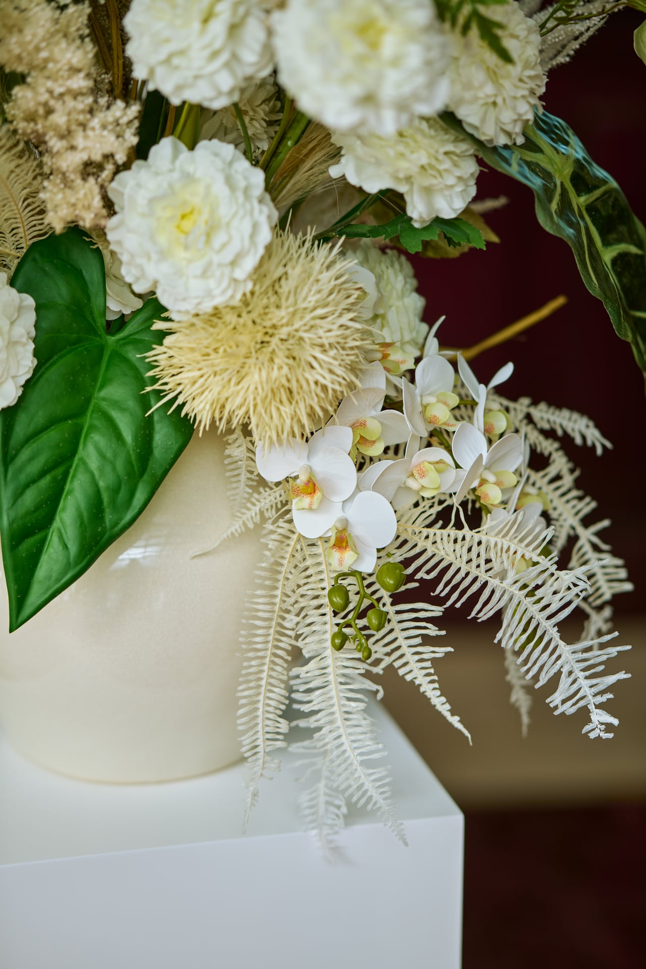 White orchid and textured floral details with green leaves.