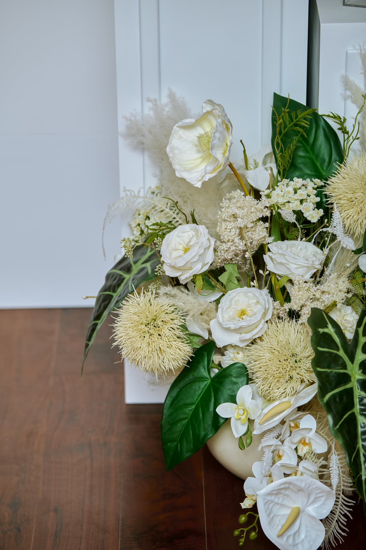 A low white and green floral arrangement with trailing orchids.